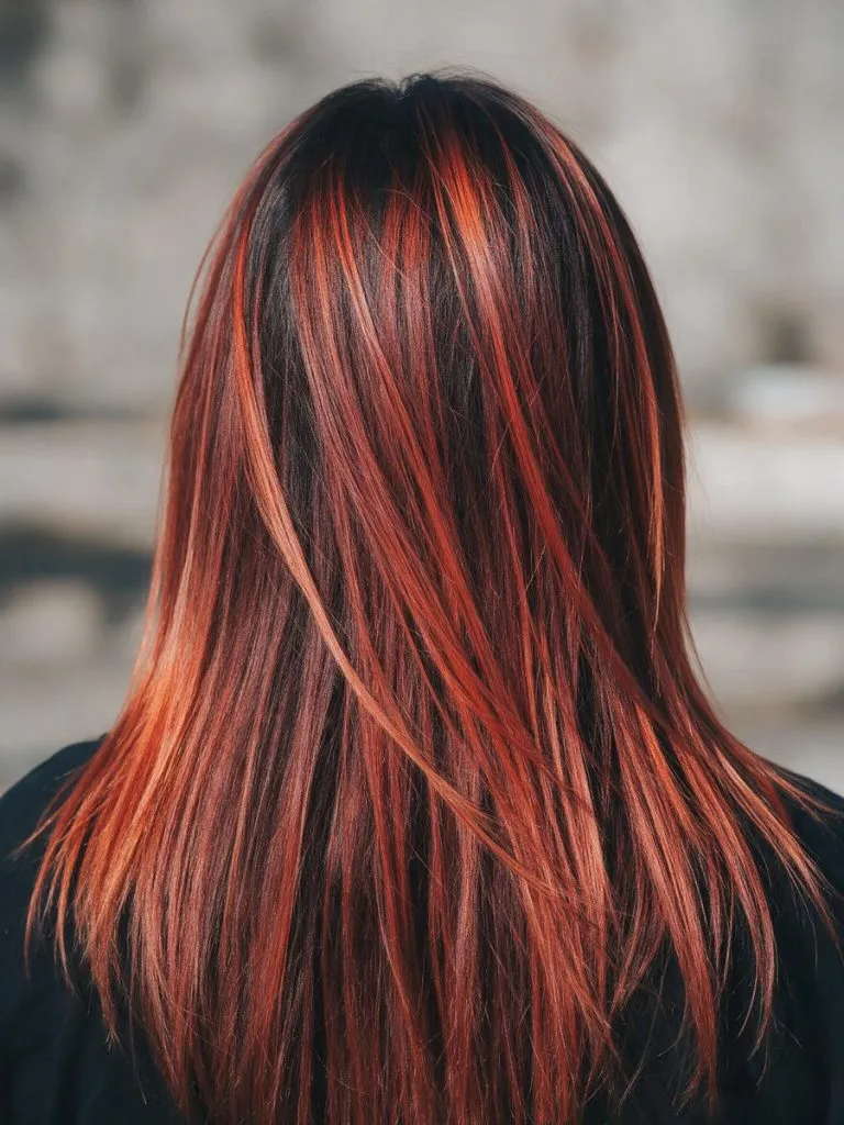 Capelli lunghi lisci con balayage rame su base scura visti da dietro