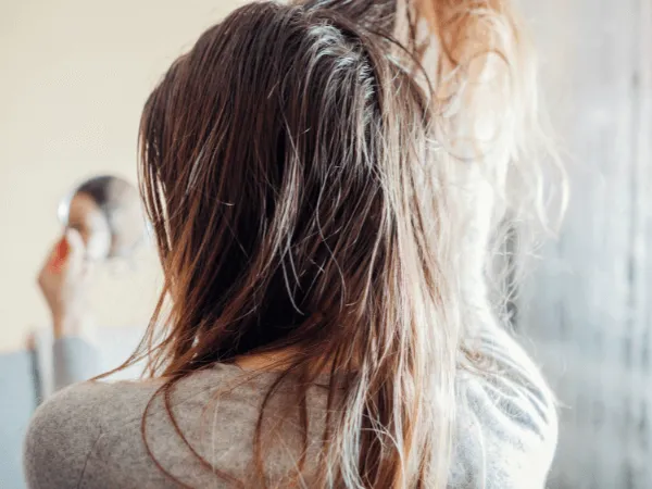 Donna che lava i capelli solo con acqua sotto la doccia senza usare shampoo