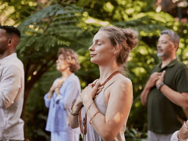 Gruppo di persone che praticano una tecnica di respirazione con le mani sul petto, attività spesso associata alla pranoterapia e ai benefici del prano come energia vitale.